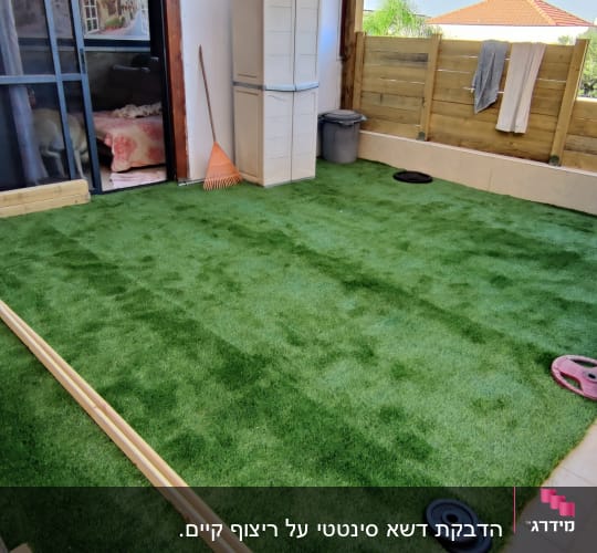 דשא סינתטי עם כלים לגינון במרפסת